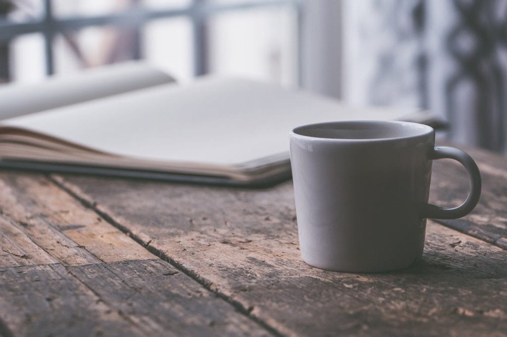 木製のテーブルの上に置かれた本とコーヒー